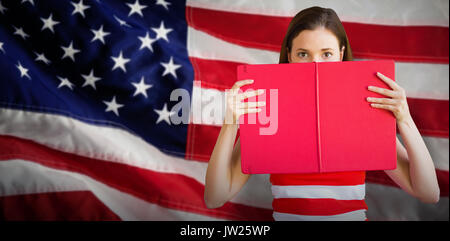 Student holding Buch über Gesicht gegen Nahaufnahme einer Flagge Stockfoto