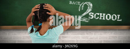 Ansicht der Rückseite des Mädchens mit den Händen am Kopf gegen greenboard an der Wand in der Schule Stockfoto