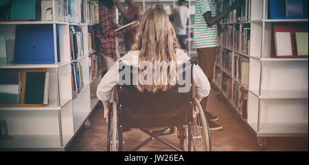 Behinderte Mädchen auf Rollstuhl in der Bibliothek in der Schule Stockfoto