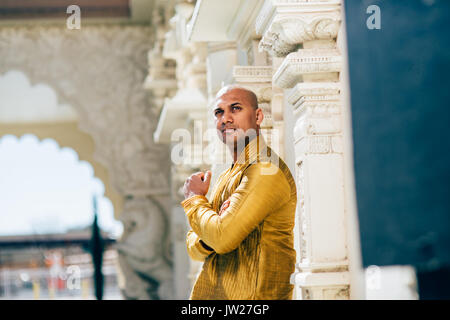 Die schönen Indischen Mann trägt ein gold Kurta und stellte an einem Tempel. Stockfoto