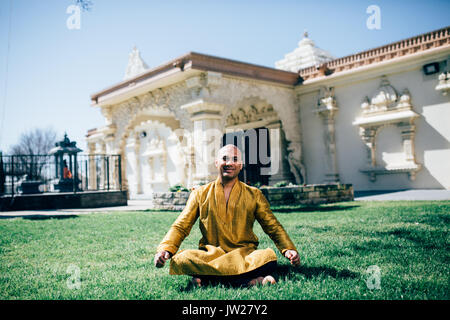 Handsom Inder Sitzen und Lächeln in einem Gold Kurta im Tempel Stockfoto
