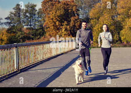 glückliches Paar mit Hund im freien laufen Stockfoto