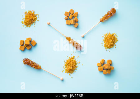 Brauner Rohrzucker, Würfel Zucker und kristalliner Zucker auf blauem Hintergrund. Ansicht von oben. Stockfoto