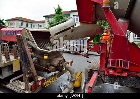 In der Nähe des Trichters auf Beton pumpen Lkw teamed oben mit einem Ready-mix Betonmischer LKW für eine inländische Sanierung Stockfoto