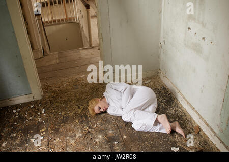 Mädchen in einer Zwangsjacke in einem verlassenen Haus Stockfoto