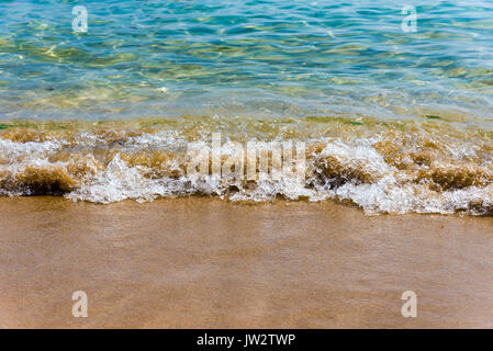 Sea Sand und eine kleine Welle Menschen tragen rote T-Shirts wenige Fußspuren am Strand weiß mit blauen Meer Wellen, Luftbild. Stockfoto