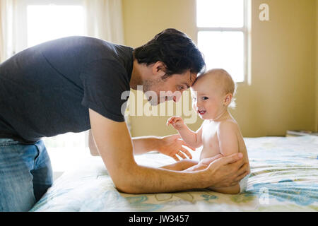 Vater spielen mit baby boy (12-17 Monate) im Schlafzimmer Stockfoto