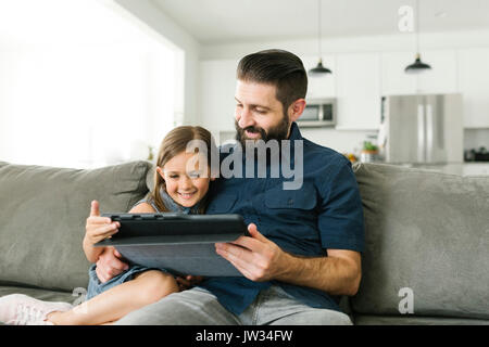 Vater mit Tochter (6-7) mit digitalen Tablette im Wohnzimmer Stockfoto
