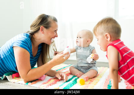 Mutter spielt mit ihr zwei Kinder (6-11 Monate, 2-3) Stockfoto