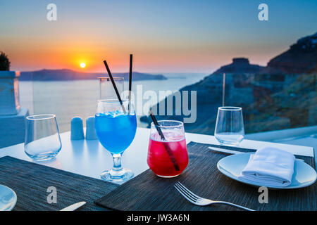 Bunte Cocktails, Imerovigli am Abend, einem Dorf in der Nähe von Fira auf der griechischen Insel Santorini mit der Bezeichnung "Balkon der Ägäis" für seine Sonnenuntergänge Stockfoto