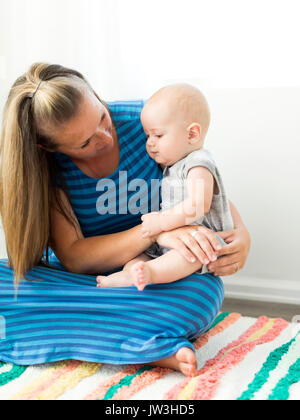 Die Mutter, die ihren Sohn (6-11 Monate) auf dem Schoß Stockfoto