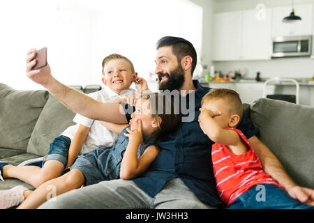 Vater mit seinen drei Kindern (2-3, 6-7) Unter selfie mit smart phone Stockfoto