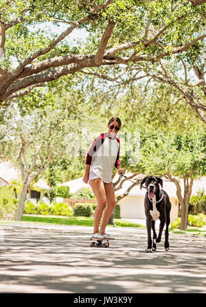 Frau auf Skate Board mit Dogge Stockfoto