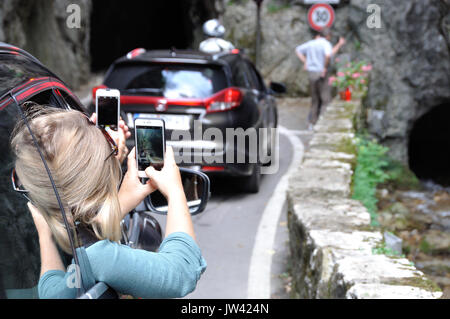 Touristen fotografieren mit dem Handy aus dem Auto an der Strada della forra, Gardasee, Italien Stockfoto