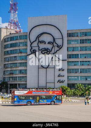 Ein Doppeldecker kubanischen Reisebus mit Touristen Pässe gefüllt durch ein Gebäude mit einem Gleichnis von Camilo Cienfuegos auf seiner Seite auf dem Platz der Revolution, Havanna Stockfoto