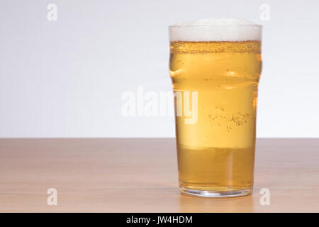 Ein frisch gezapftes, gestochen scharf, schaumiges Bier auf einem Holz Tisch mit weißem Hintergrund und Kopieren. Stockfoto