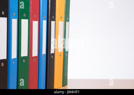 Nahaufnahme von einer Reihe von bunten Office Dokument Ordner auf einem Holz Regal mit weißem Hintergrund und Kopieren. Stockfoto