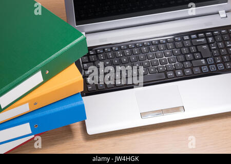 Eine ordentliche und saubere Holz Büro Schreibtisch Arbeitsbereich mit offenen Computer Laptop und ordentlich gestapelt Dokumentordnern. Stockfoto