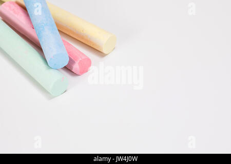 Eine Nahaufnahme von vier rote, gelbe, blaue und grüne Zeichnung Chalk klebt auf einen weißen Hintergrund mit Kopie Raum isoliert. Stockfoto