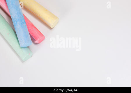 Eine Nahaufnahme von vier Farben Rot, Gelb, Blau und Grün gefärbt Zeichnung Chalk klebt auf einen weißen Hintergrund mit Kopie Raum isoliert. Stockfoto