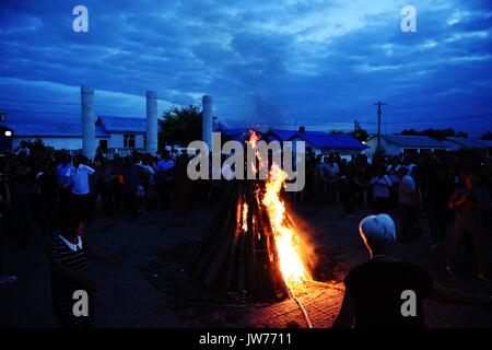 Xunke, Heilongjiang Provinz Chinas. 11 Aug, 2017. Die Menschen singen und tanzen um ein Lagerfeuer während des traditionellen Gott der ethnischen Gruppe der Brand Opfer Festival in Xunke County, im Nordosten der chinesischen Provinz Heilongjiang, Aug 11, 2017. Die Gulunmuta Festival, das wichtigste Festival für die oroqen Menschen, wurde als einer der ersten Charge von Chinas immaterielle Kulturerbe im Jahr 2006 aufgeführt. Credit: Wang Jianwei/Xinhua/Alamy leben Nachrichten Stockfoto