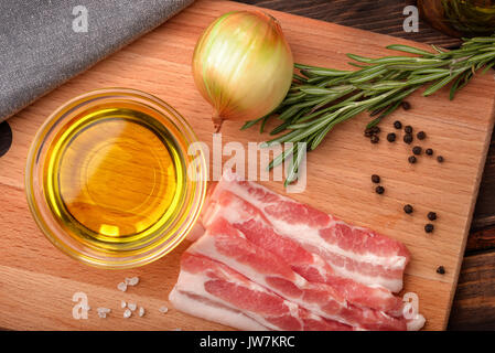 Blick von oben auf die rohen Schinken, Olivenöl, Gewürze und Kräuter auf Holz Schneidebrett Stockfoto