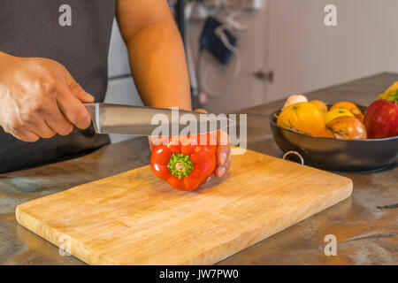 Koch schneiden Red Paprika auf hölzernen breit. Stockfoto