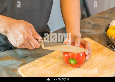 Koch schneiden Red Paprika auf Holz Breite Stockfoto