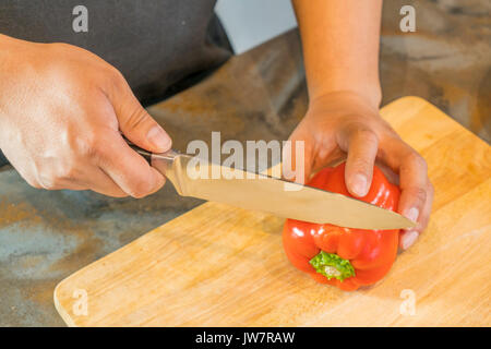 Koch schneiden Red Paprika auf hölzernen breit. Stockfoto