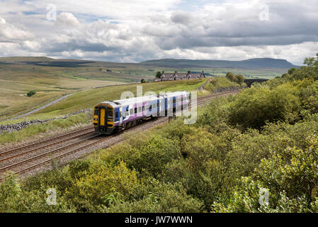 Sprinter Pkw Zug nähert sich Ribblehead Station, North Yorkshire, auf der Settle-Carlisle Railway Line. Pen-y-Ghent Peak im Hintergrund. Stockfoto