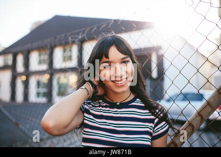 Porträt der schönen jungen Frau, die im Freien und lächelnd. Hispanic weiblichen Blick auf Kamera. Stockfoto