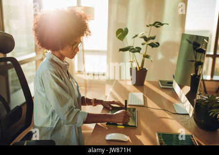 Junge hipster Graphic Designer Frau mit digitaler Grafik Tablett und modernes Arbeiten im Büro. Professionelle female Retoucher an modernen Sitzen arbeiten Stockfoto
