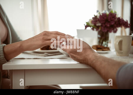 Blick auf Älteres Paar Hände halten beim Frühstück 7/8 Stockfoto