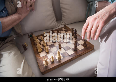 Schuß von Senior paar Schach spielen beim Sitzen auf dem Sofa zu Hause 7/8 Stockfoto