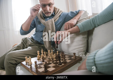 Senior paar Schach spielen beim Sitzen auf dem Sofa zu Hause Stockfoto