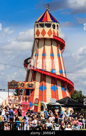 Menschenmengen sammeln in der Nähe der Stände- und Unterhaltungsviertel, mit einem traditionellen Helter Skelter Spiralrutsche, Jimmy's Festival, Ipswich, Suffolk, Großbritannien Stockfoto