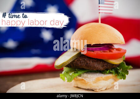 Digital zusammengesetzten Bild der Zeit zu den glücklichen Tag der Arbeit Text gegen Burger auf Platte gegen amerikanische Flagge Stockfoto