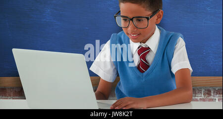 Schüler mit Laptop am Tisch gegen den blauen Wand über brick wall Stockfoto