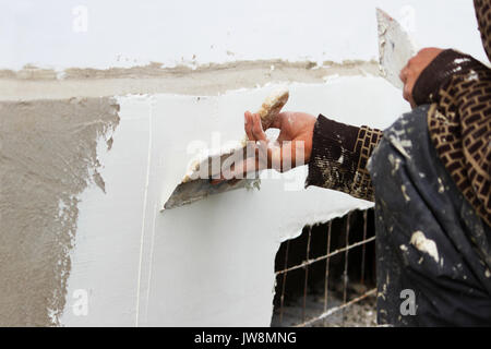 Bauarbeiter Gipser mit Wand verputzen Tools renovieren Wohnung Haus. Gipser Renovierung outdoor Mauern des alten Hauses. Bau Ausbauarbeiten Stockfoto