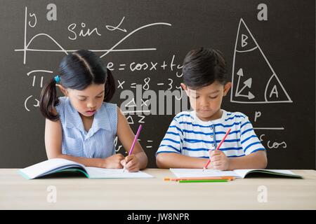 Digital composite der Studenten in Tabelle schreiben gegen Grau Tafel mit Bildung und Schule Grafiken Stockfoto