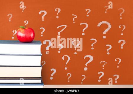 Digital composite der Bücher auf den Tisch gegen orange Tafel mit Fragezeichen Stockfoto
