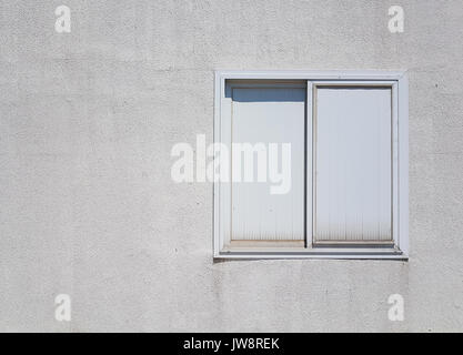 Weißer Kunststoff Fenster auf groben weißen Beton Wand Stockfoto