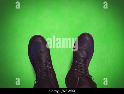 Digital composite der Schwarze Schuhe an den Füßen mit grünem Hintergrund Stockfoto