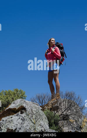 Niedrige Engel Blick auf weibliche Wanderer stehen auf Rock gegen blauen Himmel Stockfoto