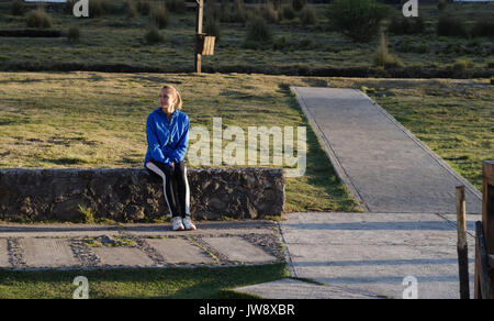 Weibliche Athleten sitzen auf stützmauer während der sonnigen Tag Stockfoto