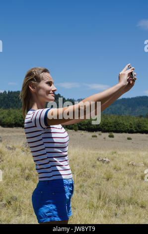 Seitenansicht des lächelnd weibliche Wanderer unter selfie beim Stehen auf Feld Stockfoto