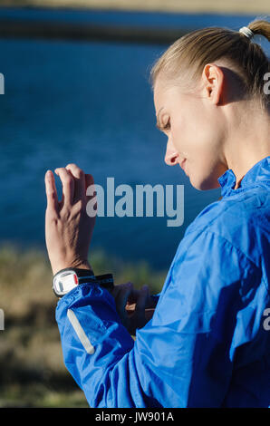 Seitenansicht der Frau tragen Armbanduhr beim Stehen gegen See Stockfoto