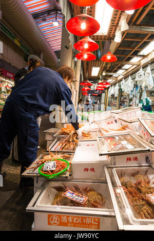 Low-Winkel auf Abschaltdruck Eigentümer Organisation grosse orange Krabben in den Behältern auf einem Stand in der omicho indoor Lebensmittelmarkt in Kanazawa in Japan. Stockfoto