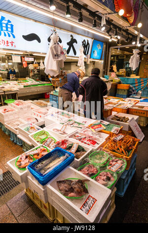 Frische Meeresfrüchte mit verschiedenen Arten von Fischen in Kunststoffbehältern auf Verkauf Stall in der Markthalle, Omicho, in Kanazawa, Japan. Nur wenige Menschen. Stockfoto