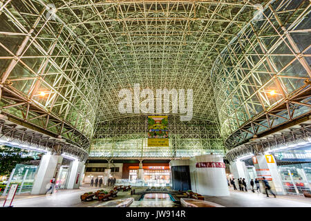 Kanazawa Station, Japan, großem Betrachtungswinkel aus Glas und Stahl Motenashi Dome Innenraum bei Nacht, nur wenige Menschen. Station Eingang im Hintergrund. Stockfoto